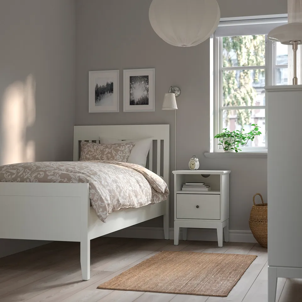 Cosy bedroom with ÅRSTID lamp, white, linen shade, adjustable, beside bed, small, natural light, grey walls.