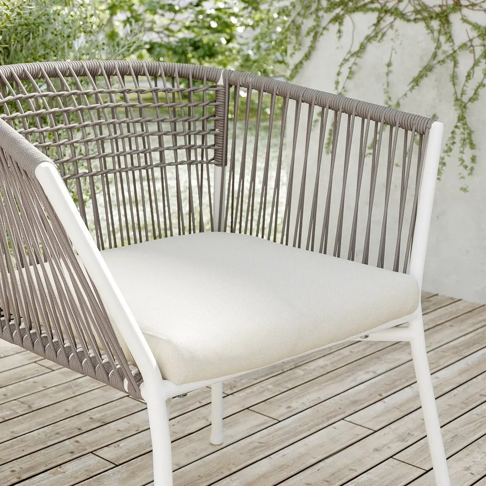 Modern outdoor chair, white frame, woven grey, beige cushion, wooden deck setting.
