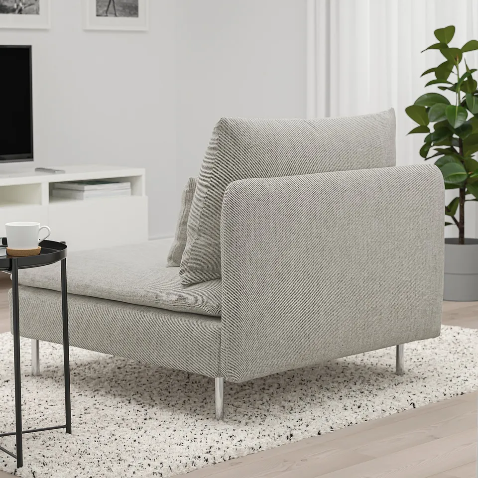 A modern, low-profile, light grey sofa with metal legs, loose cushions, and a side table with a coffee cup.
