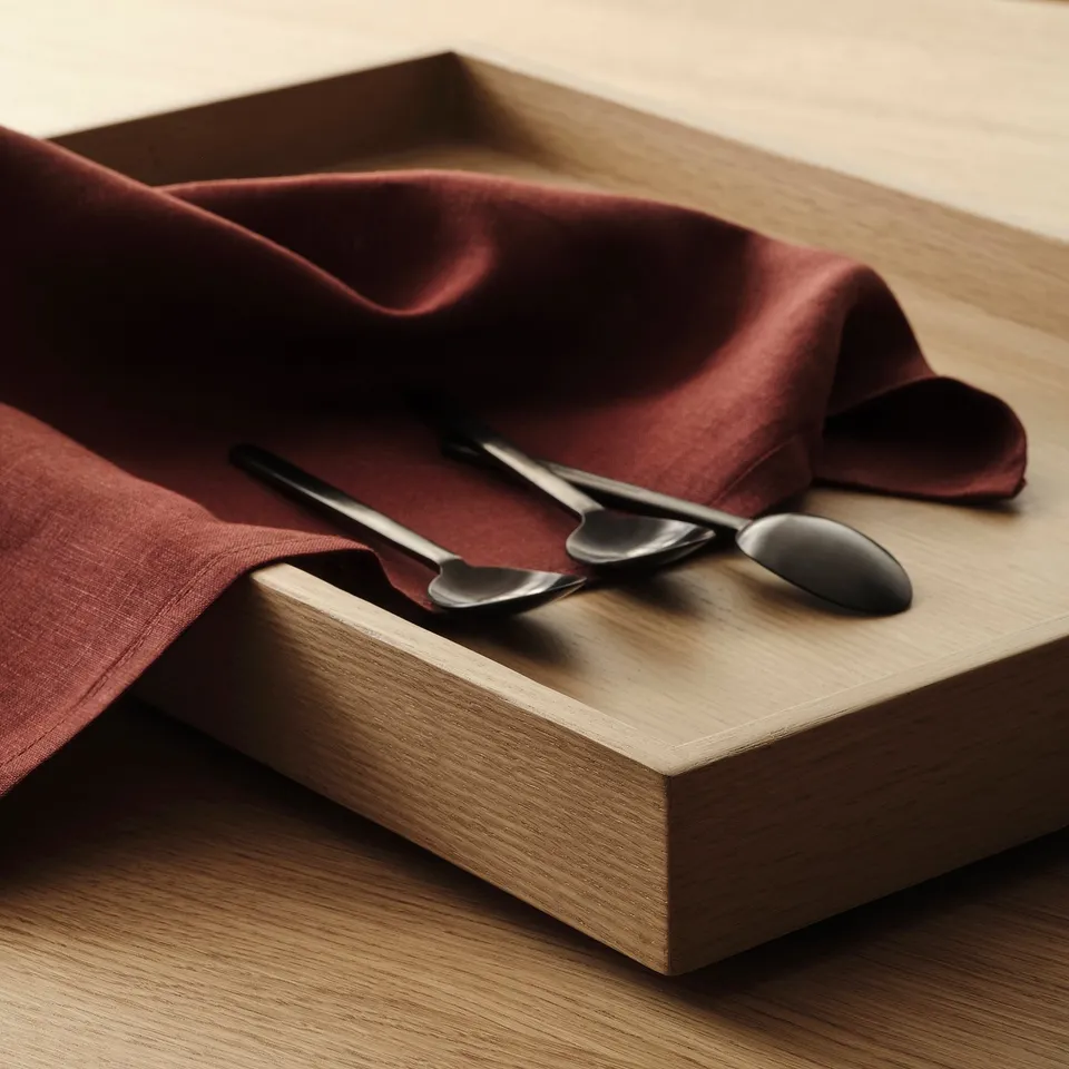 Wooden tray with smooth, dark red cloth and sleek black utensils, showcasing high-quality craftsmanship.