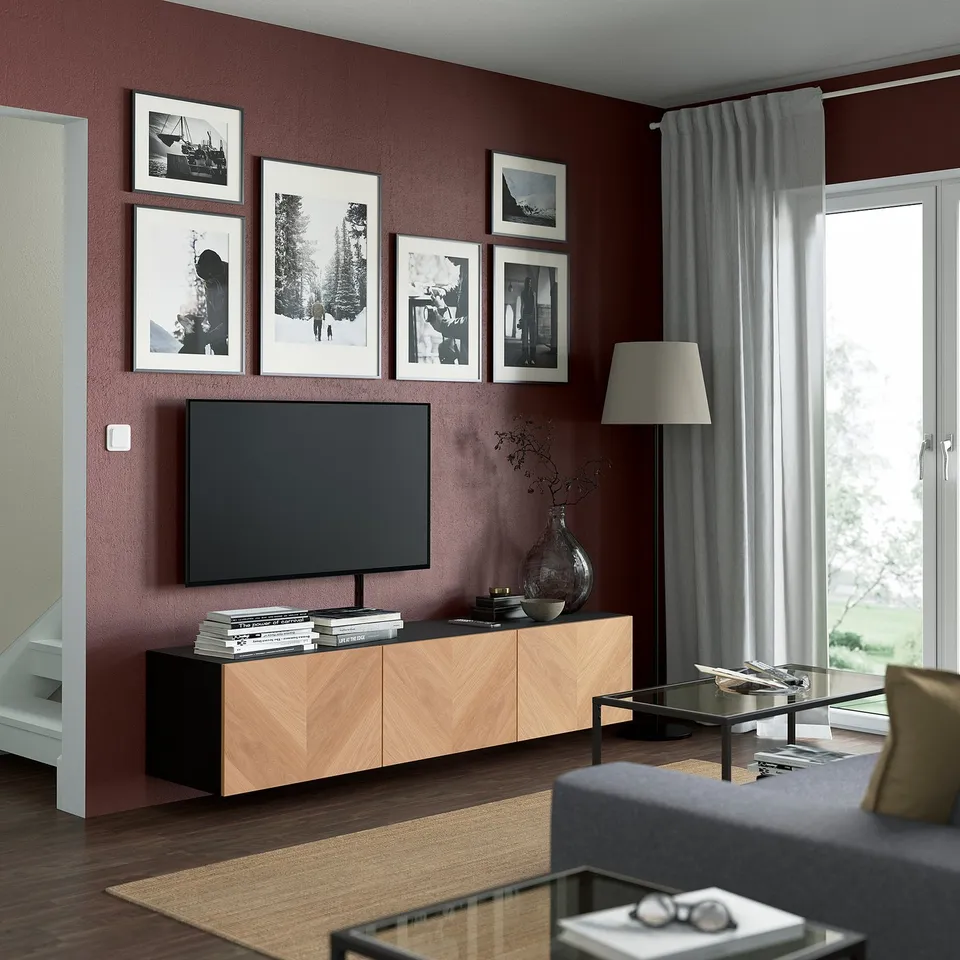 Modern living room with maroon walls, tv, wooden bench, lamp, coffee table, sofa, and glass door.
