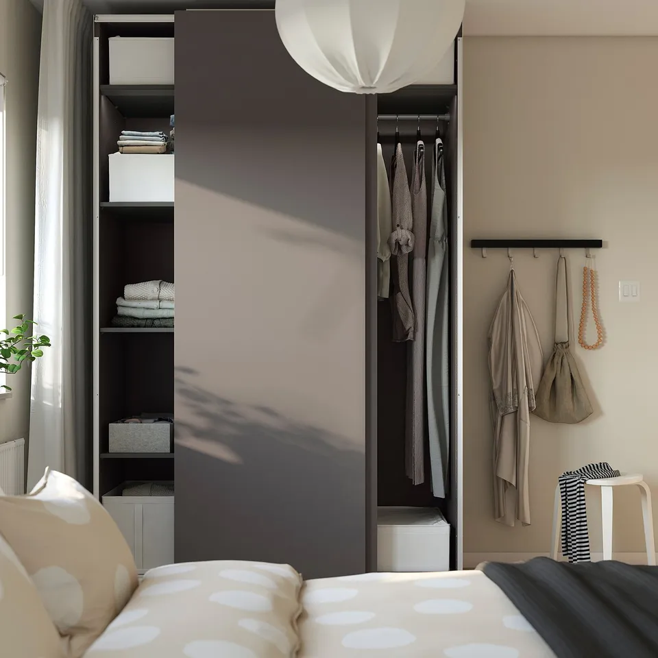 Modern bedroom with wardrobe, sliding doors, shelves, hanging clothes, organised linens, pendant light, and cosy bed with polka dot pillows.