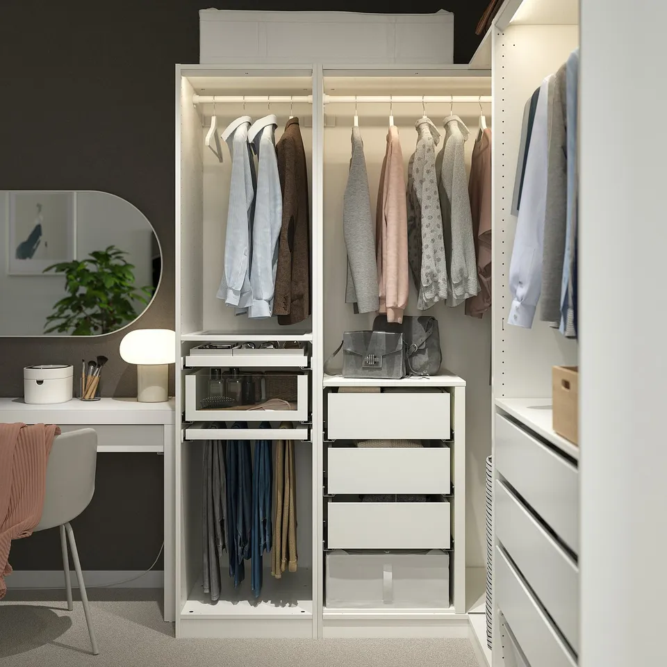 A white PAX wardrobe with compartments for hanging clothes, pants, and accessories, including a vanity area.