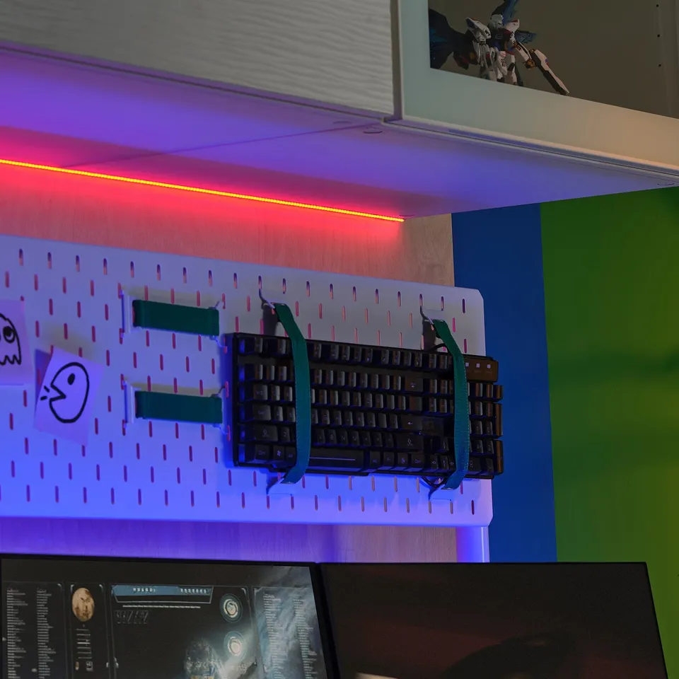 Desk with KABBLEKA led red light strip above pegboard and keyboard with green straps.