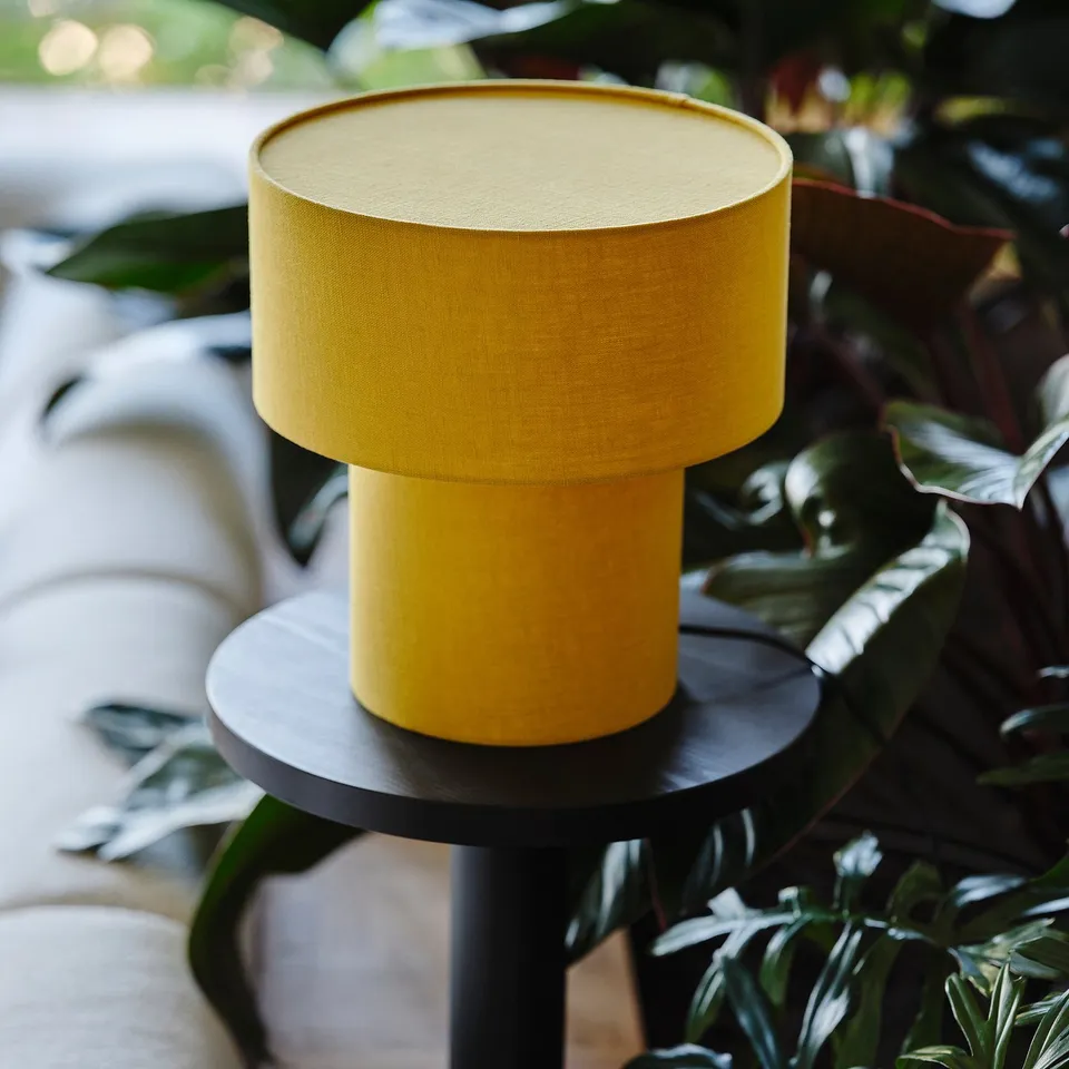 Bright yellow STOCKHOLM 2025 table lamp, round & cosy. Size similar to a large book.