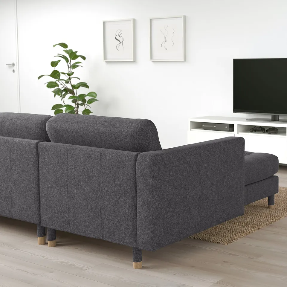 Minimalist living room with dark sofa, tv, plant, art.