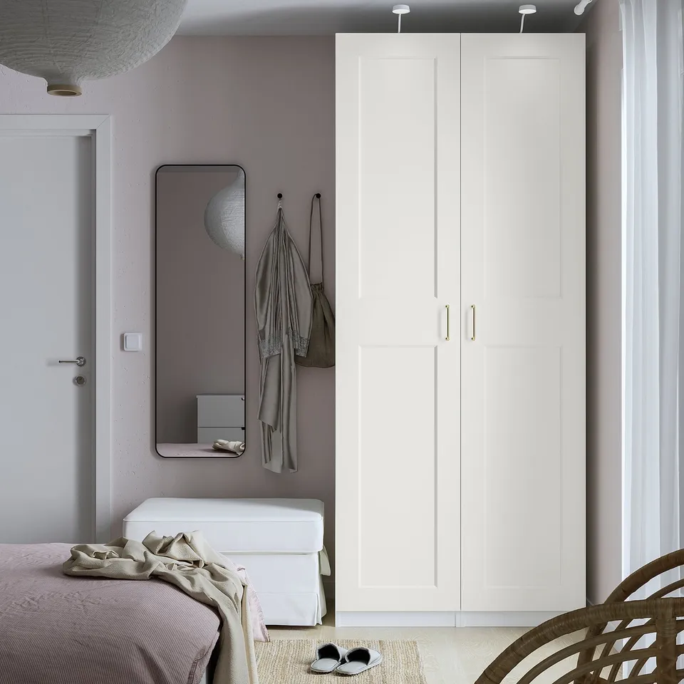 Modern bedroom with PAX wardrobe in white next to a mirror and bed.