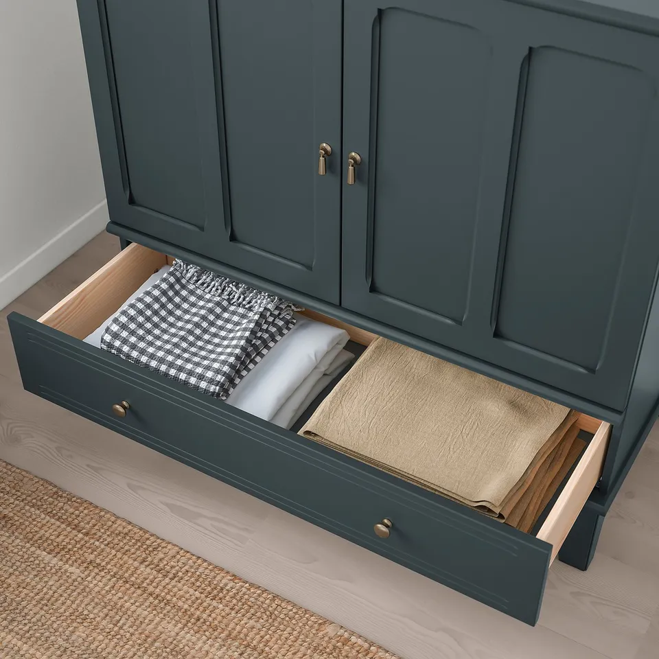 Image shows green cabinet with open drawers, holding folded towels and paper. Soft-close feature evident.