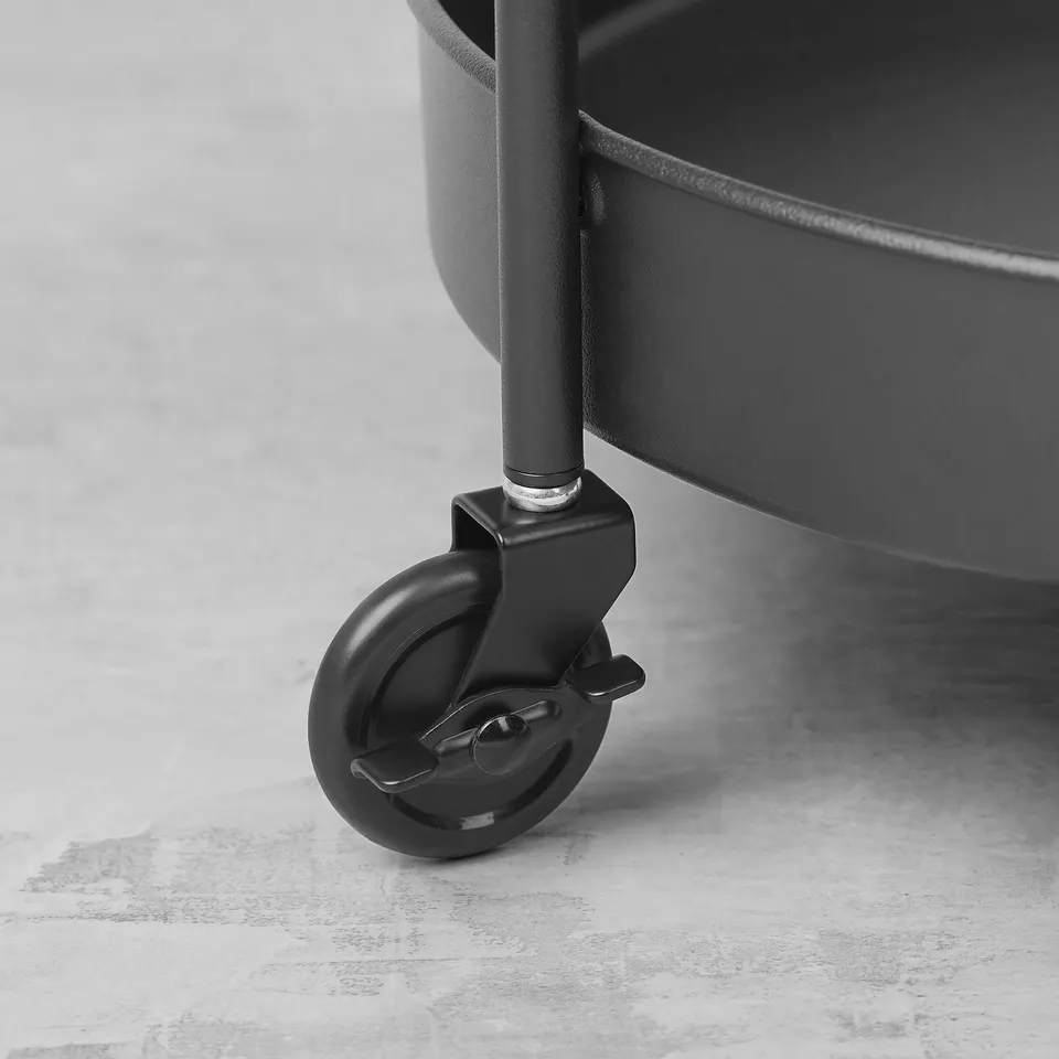 Black metal trolley wheel with locking mechanism on smooth surface.