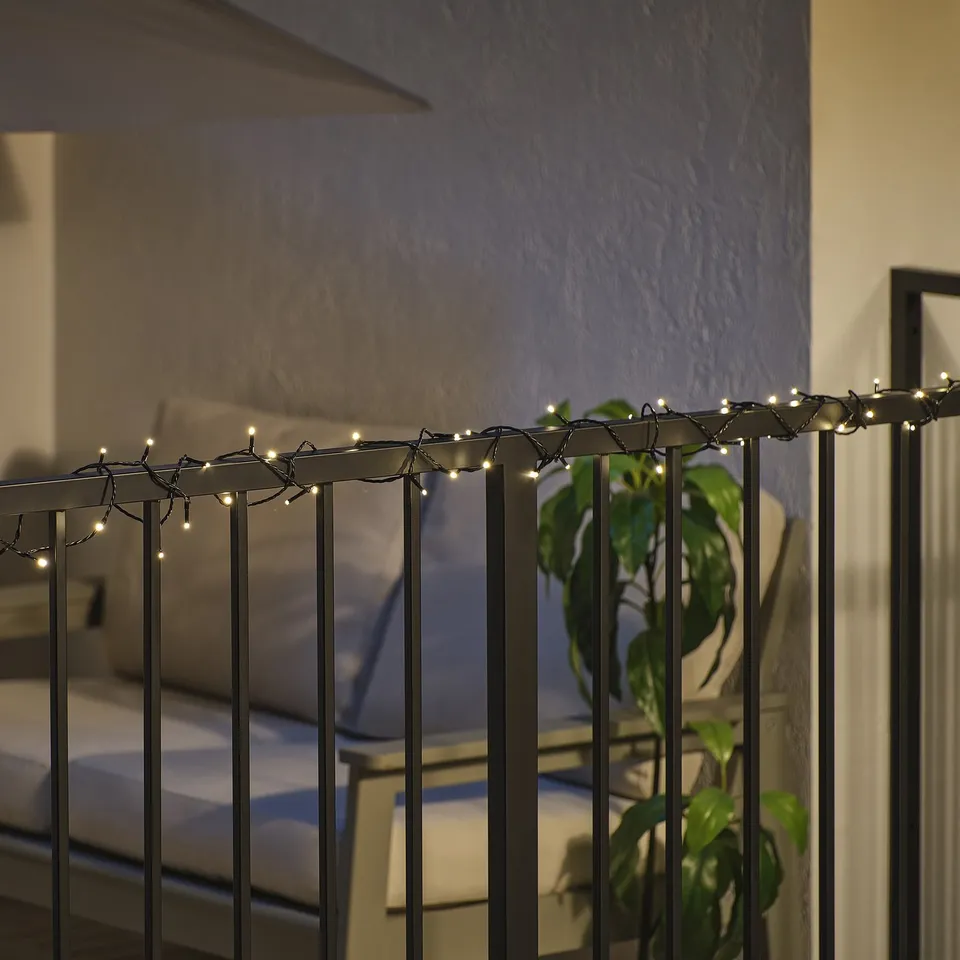 String lights on balcony railing illuminate night, creating ambiance.