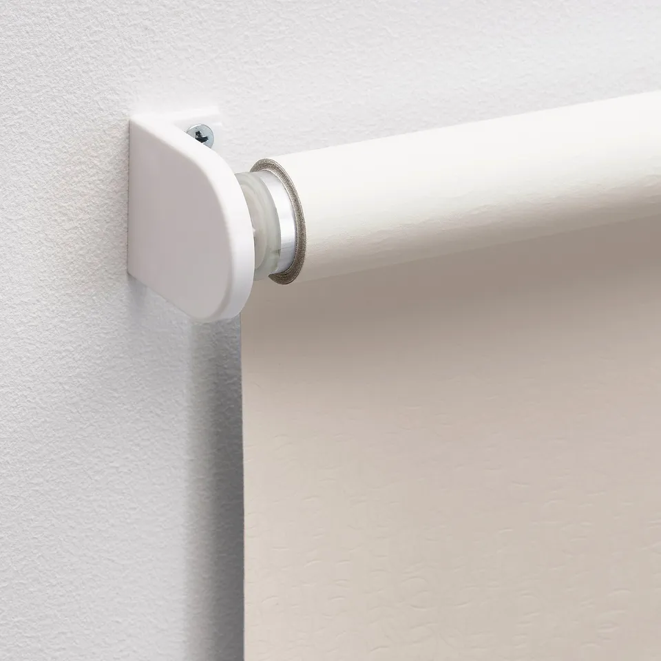 White roller blind bracket mounted on wall, showcasing silent, block-out functionality.