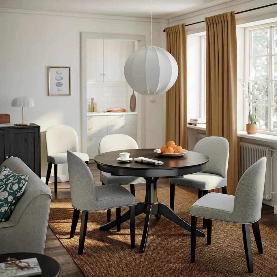 Modern dining setup with beige ROSENTORP chair, black round tables, oranges, and grey sofa.