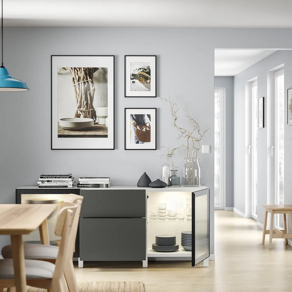 Modern dining area with grey BESTÅ sideboard, light wooden table and chairs, decorative vases, and wall art.