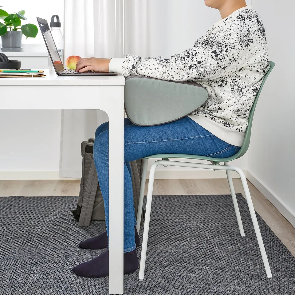 Person working at white desk with laptop, using a blue-green footrest, promoting good posture and comfort.