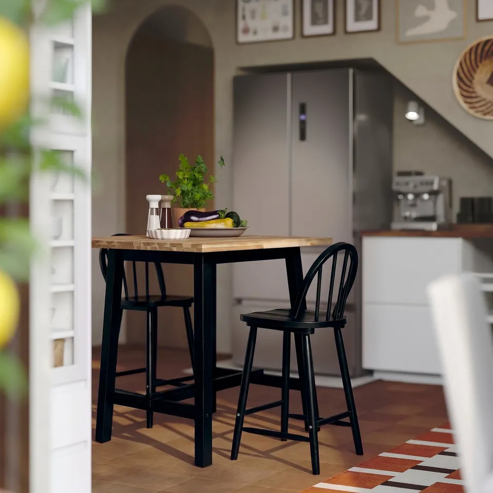 Small black wooden bar table and chairs in kitchen.