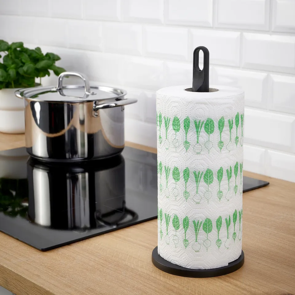 Black kitchen roll with green leaf on wooden counter.