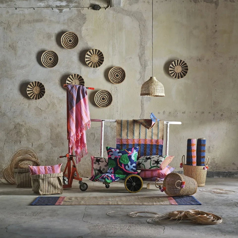 Cosy room with colourful rug, striped pillows, baskets, and wall hangings.