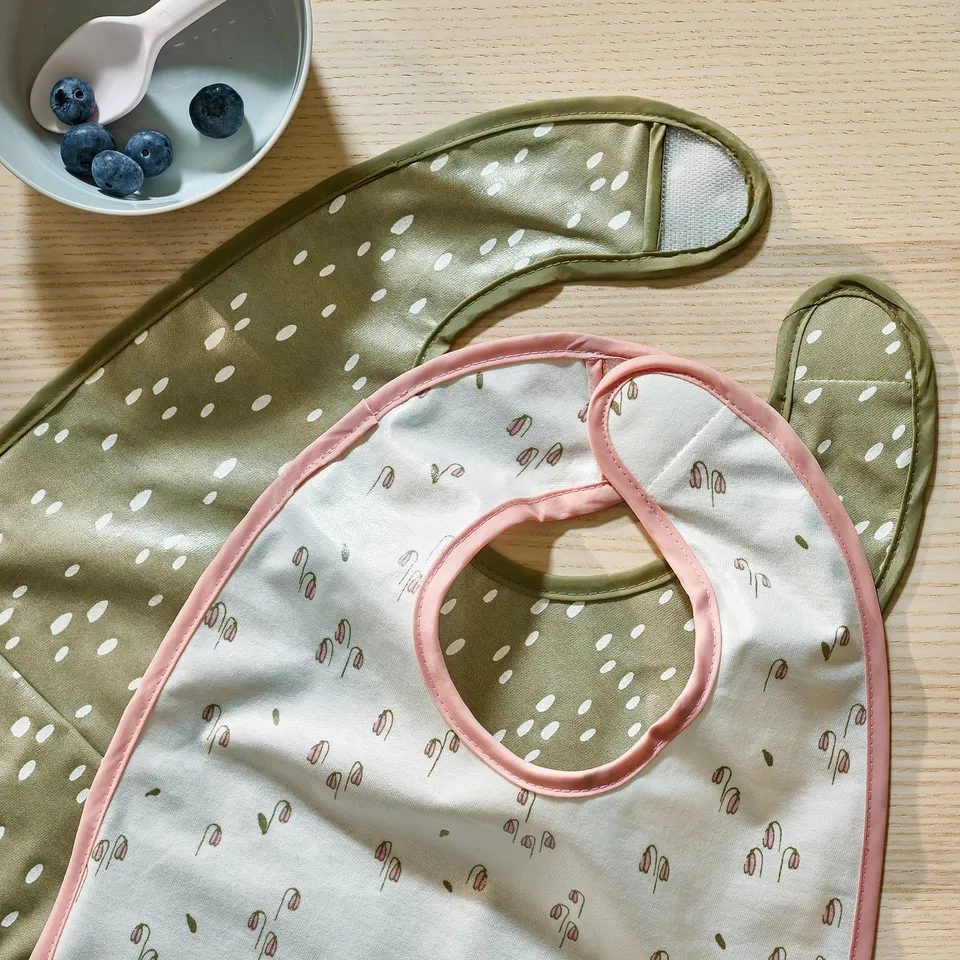 Colourful bibs with floral and dotted patterns laid out, showcasing quality materials and designs.