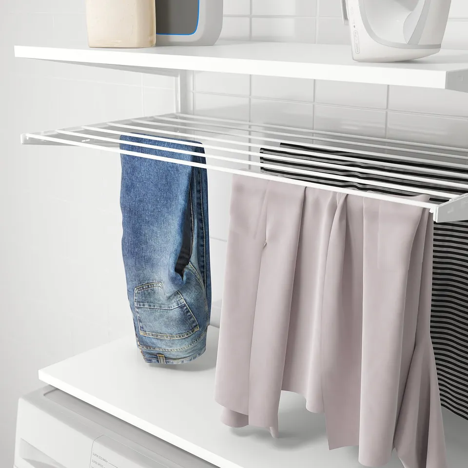 BOAXEL wall storage: drying rack holds jeans, pink pants, and striped shirt. Easy laundry organisation.