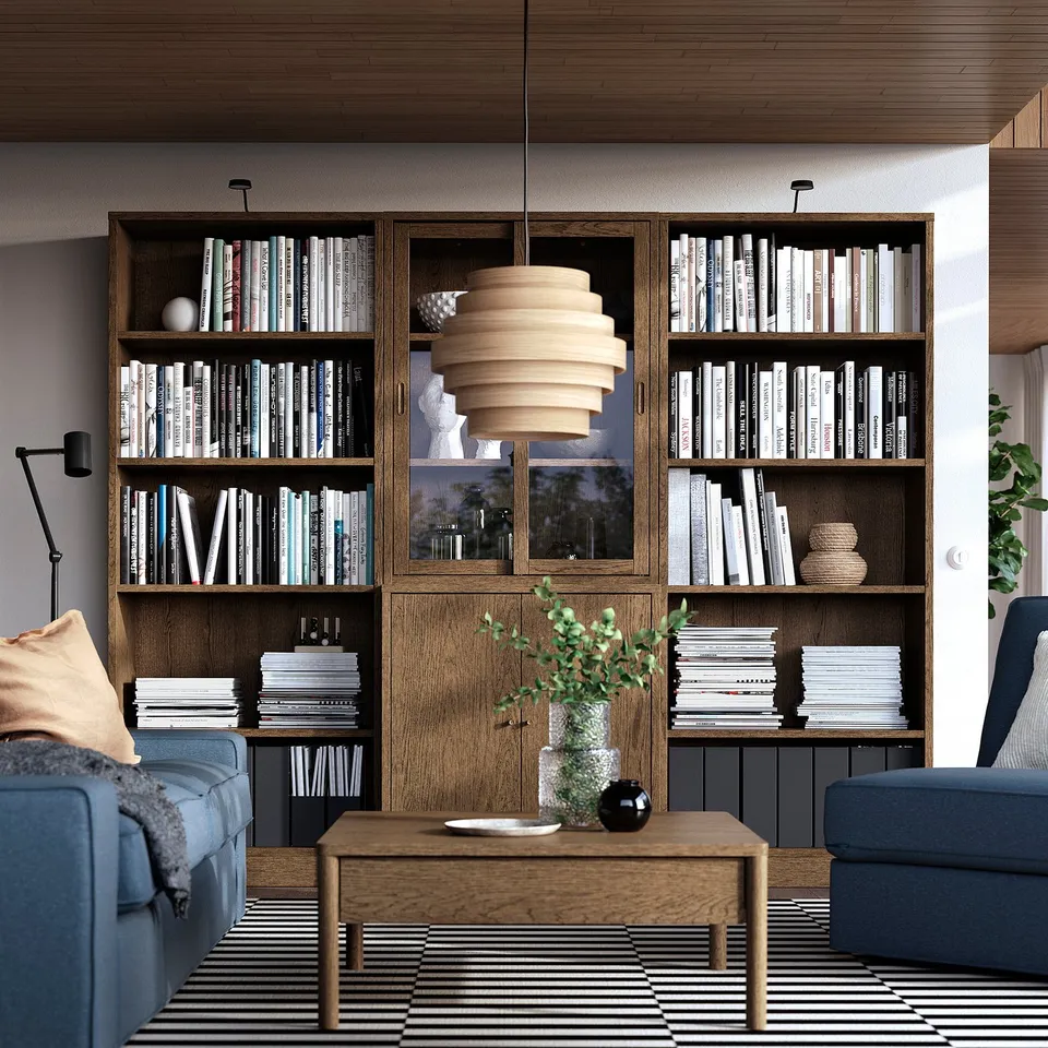 Wooden bookshelf with books & decor. Blue sofas, coffee table, rug, pendant lamp.