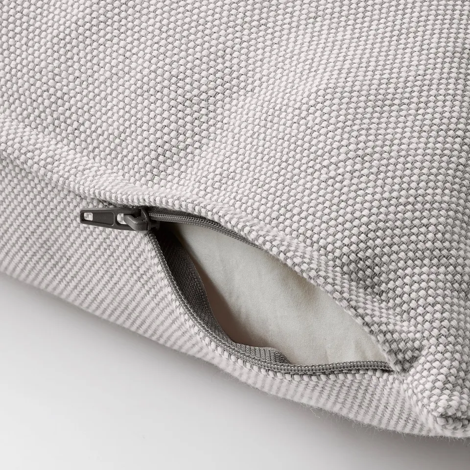 Close-up of fabric cushion with an open zip on grey and white textured cover.