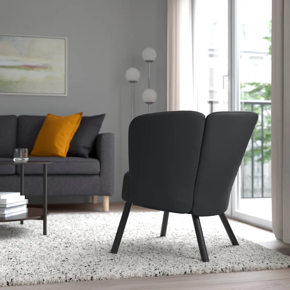 Modern living room with grey armchair, sofa, and coffee table. Yellow pillow, rug, and balcony accessible.