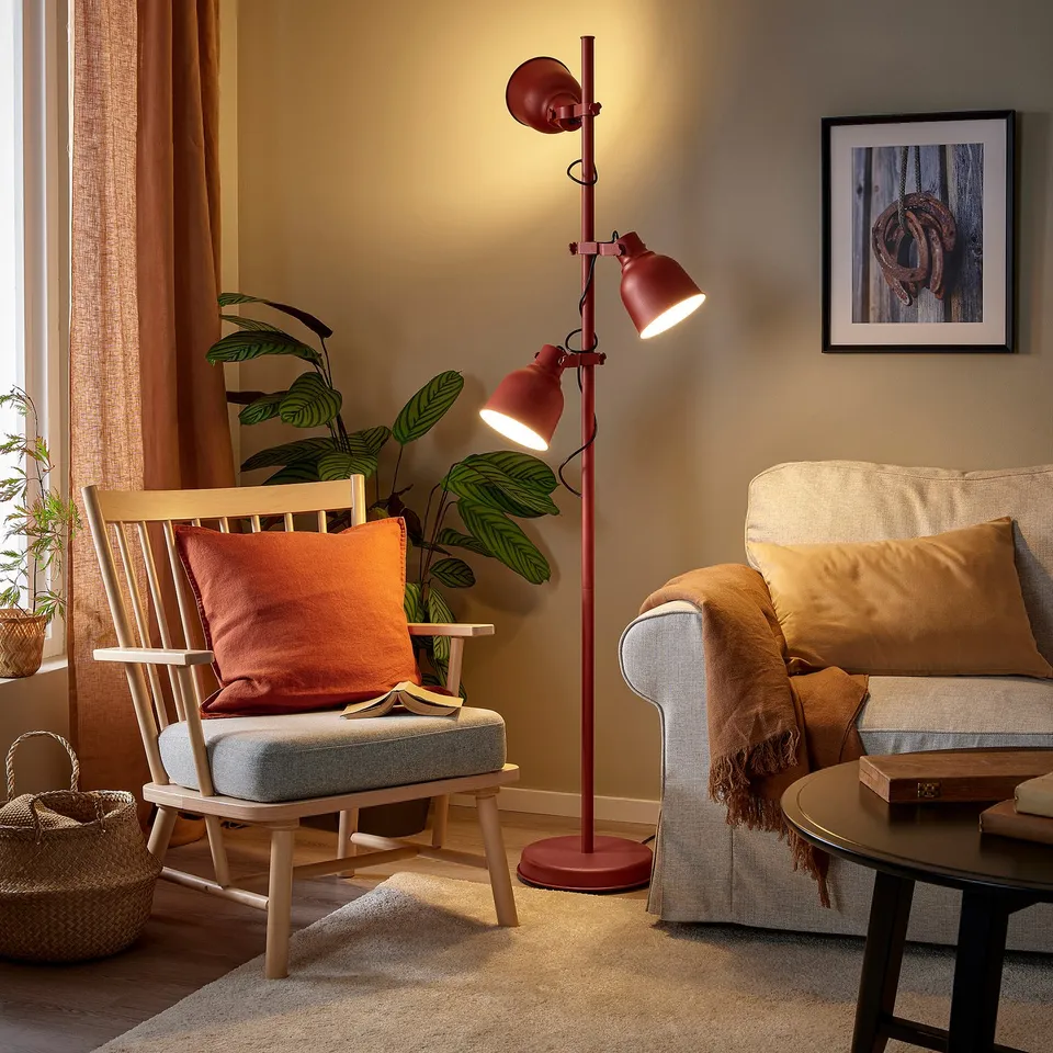 Living room with rust-red HEKTAR lamp beside grey chair and beige sofa.