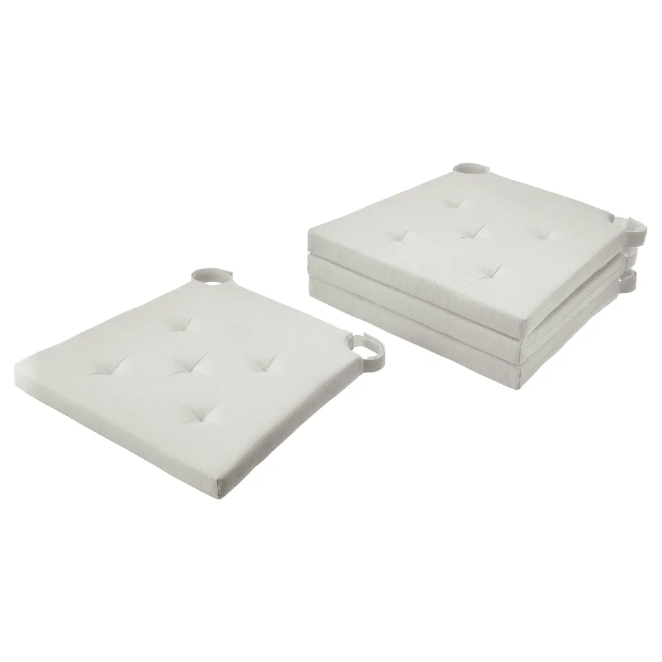 Two light-colored, square-shaped chair cushions with tufted design and handles, stacked neatly.