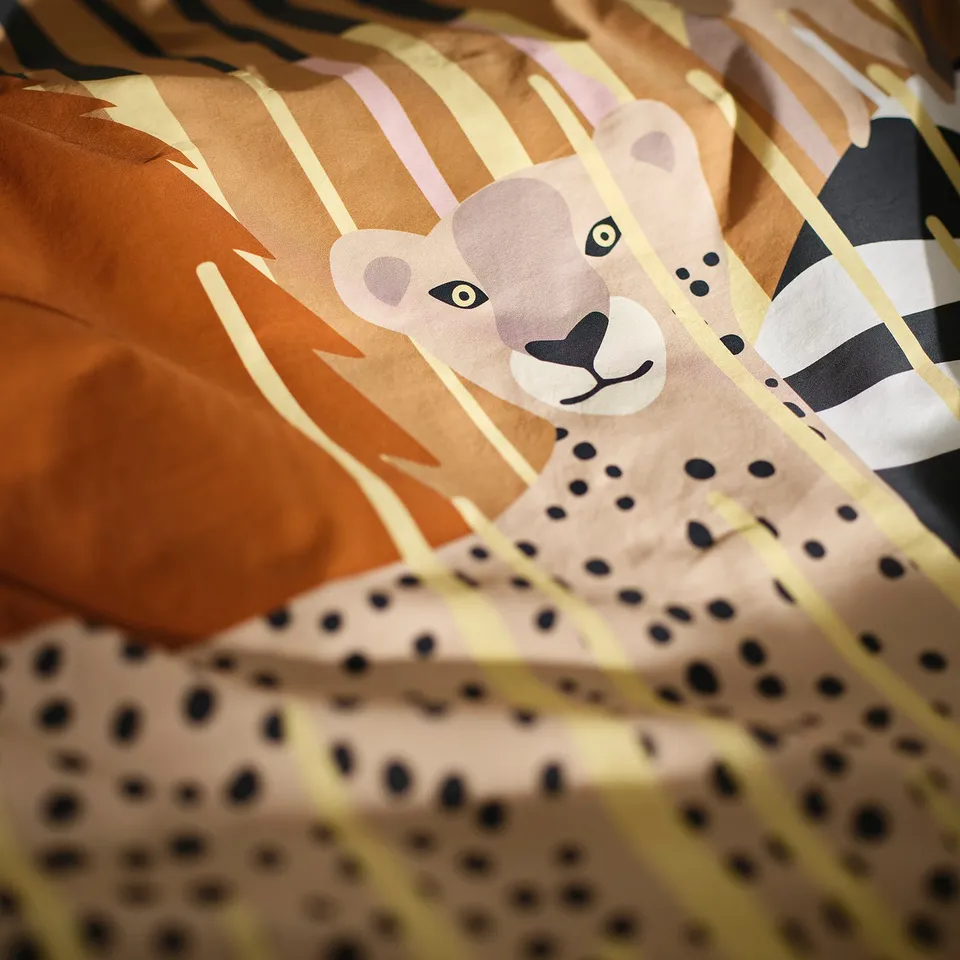 Close-up of a soft duvet with a cute leopard and grass pattern. Detail shows vibrant print quality.