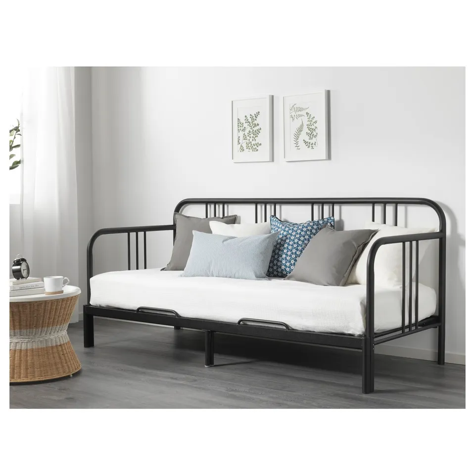 Modern black metal daybed with two pillows in a living area, showcasing its versatility as a sofa or guest bed.