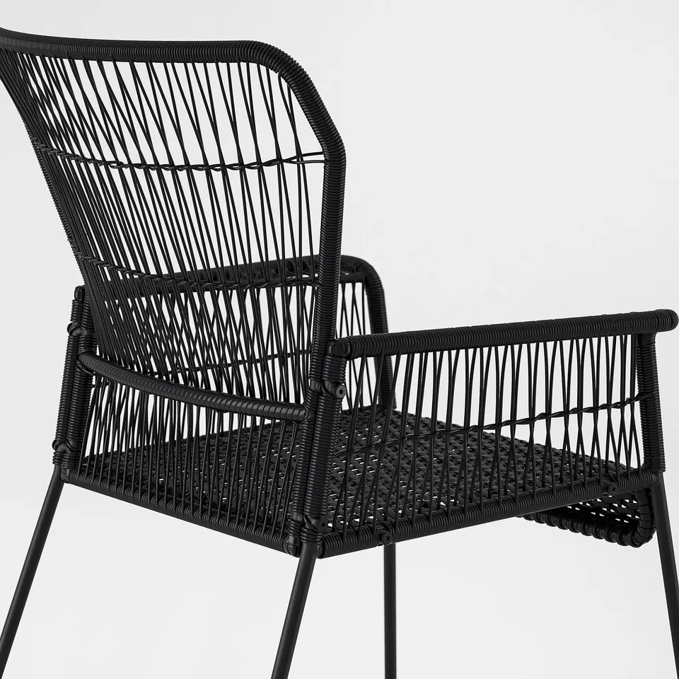 Black wicker chair with sturdy legs, intricately woven seats and backrest, ideal for outdoor use.