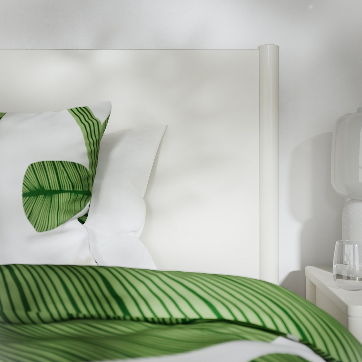 Modern white bed with green leafy pattern duvet, crisp white pillows, smooth edges, and soft-close drawers. Minimalist and high-quality design.