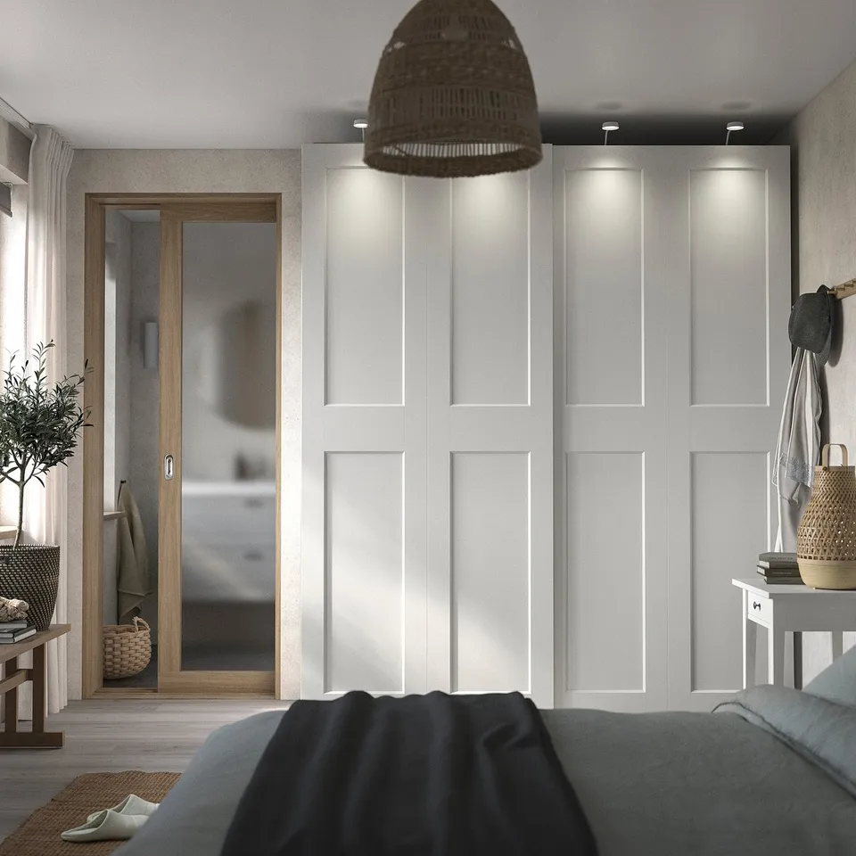 Modern bedroom with white PAX wardrobe, grey bedding, wicker pendant light, and wooden accents.