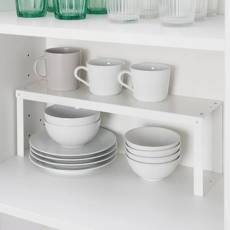 White cabinet shelf with VARIERA organiser holding mugs, bowls, and plates.