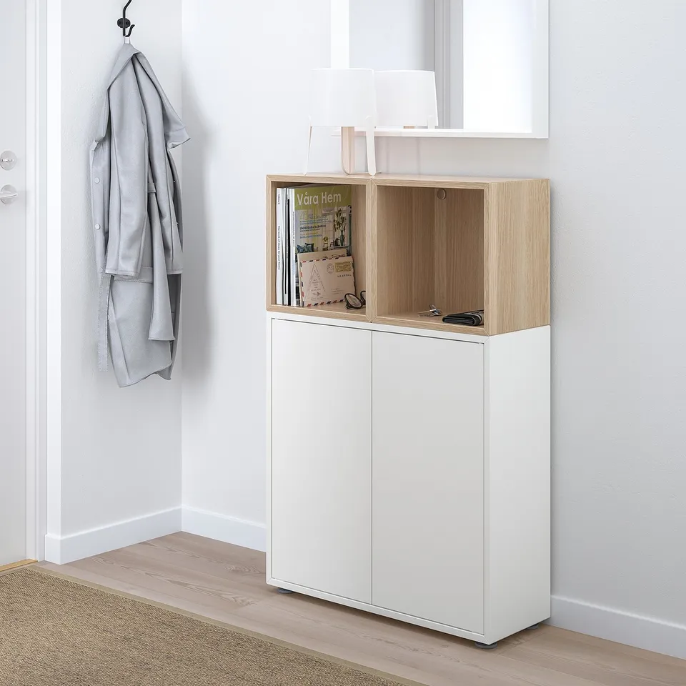 White EKET hall cabinet, tall, mixed storage, wood lamp, grey sweater.
