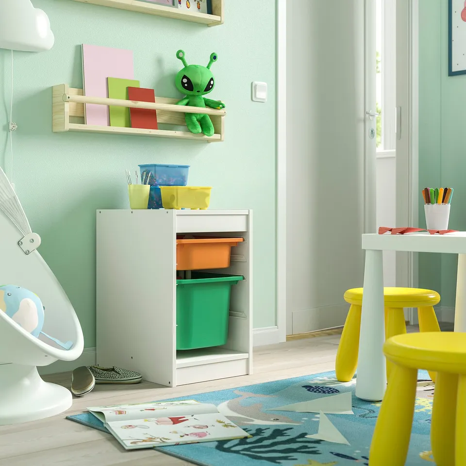 Kids playroom with TROFAST storage, colourful bins, alien toy, yellow stools, art table, multicolor rug.