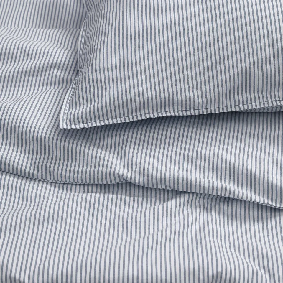 Close-up of neatly folded striped bedsheet and pillowcases, showcasing quality cotton fabric and precise stitching.