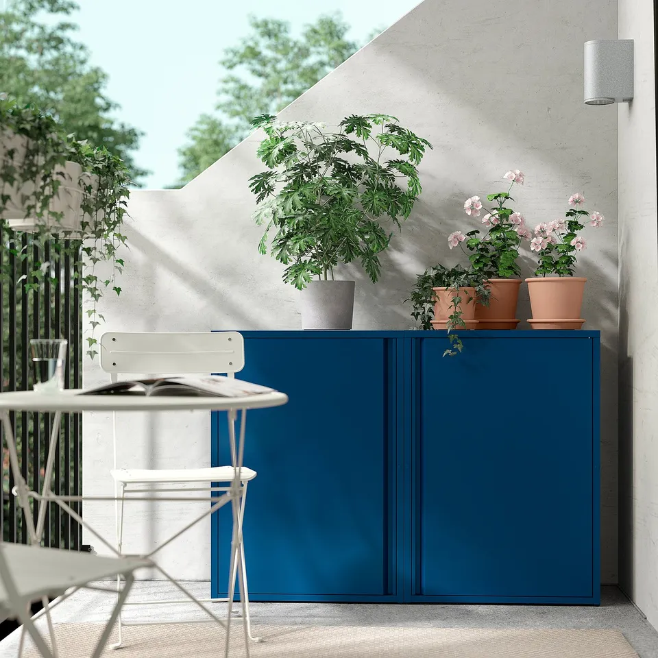 Blue SUNDSÖ storage cabinet on patio with plants and chairs.