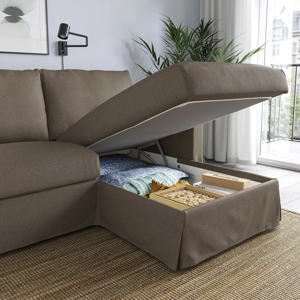 Modern sofa with pull-out storage. Chaise lid open, revealing blankets and books.