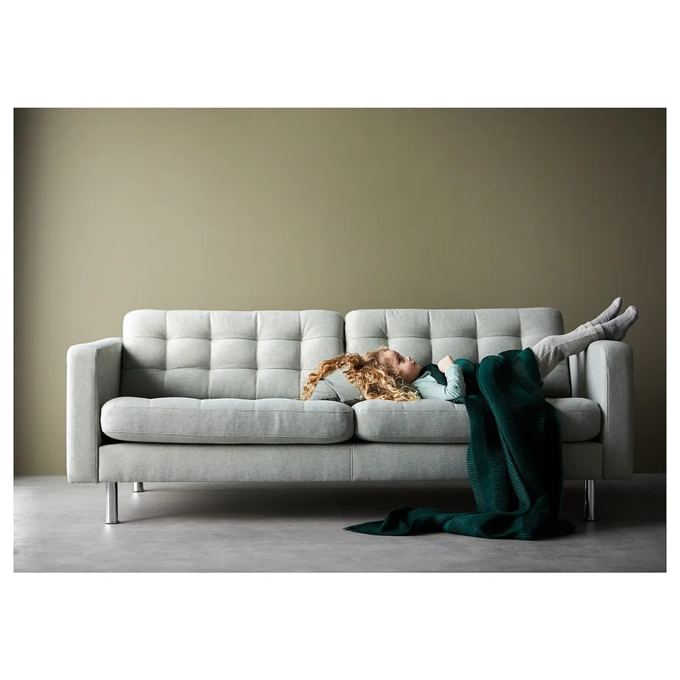 Person sitting on sofa with blanket.
