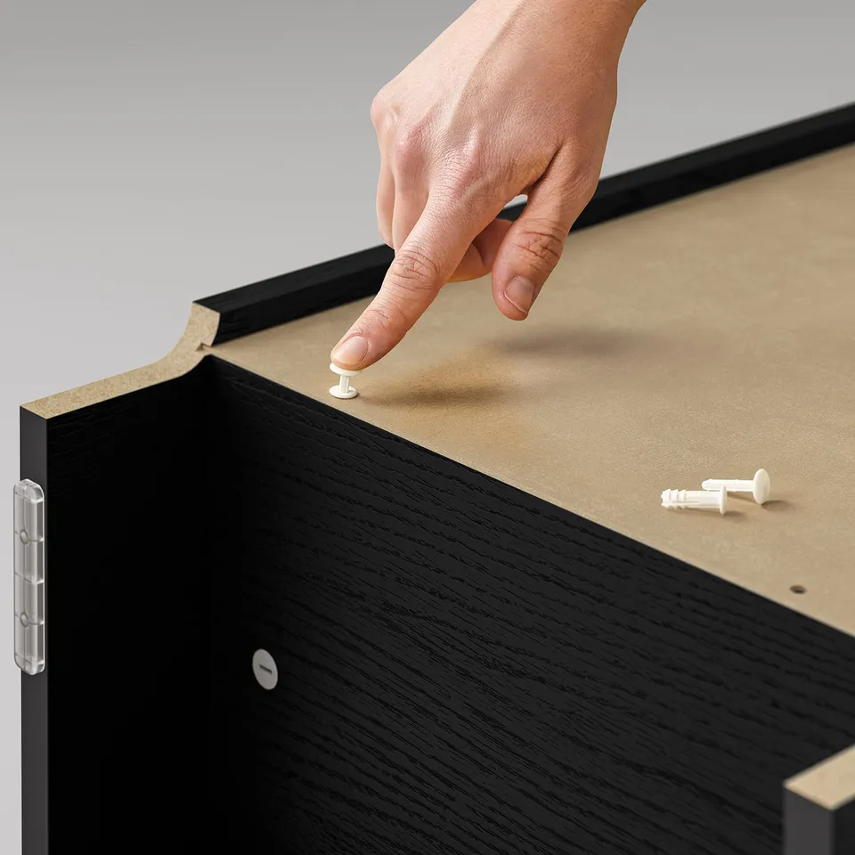 A hand placing a small white pin on a black pin board.