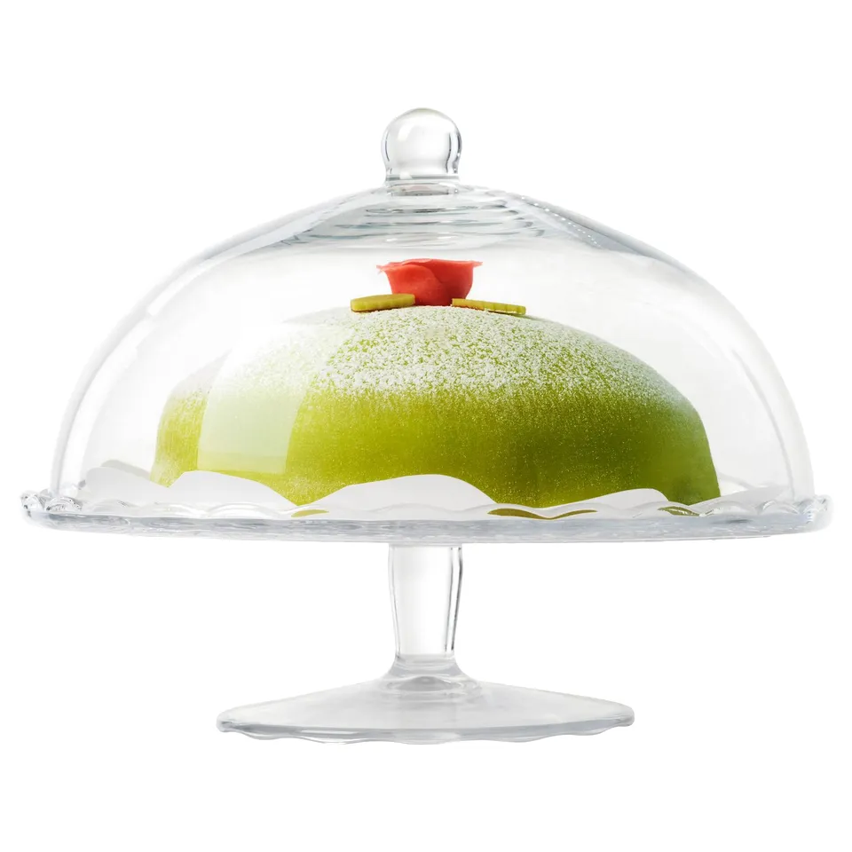 Clear glass cake stand with lid displays green cake, keeps flies out.