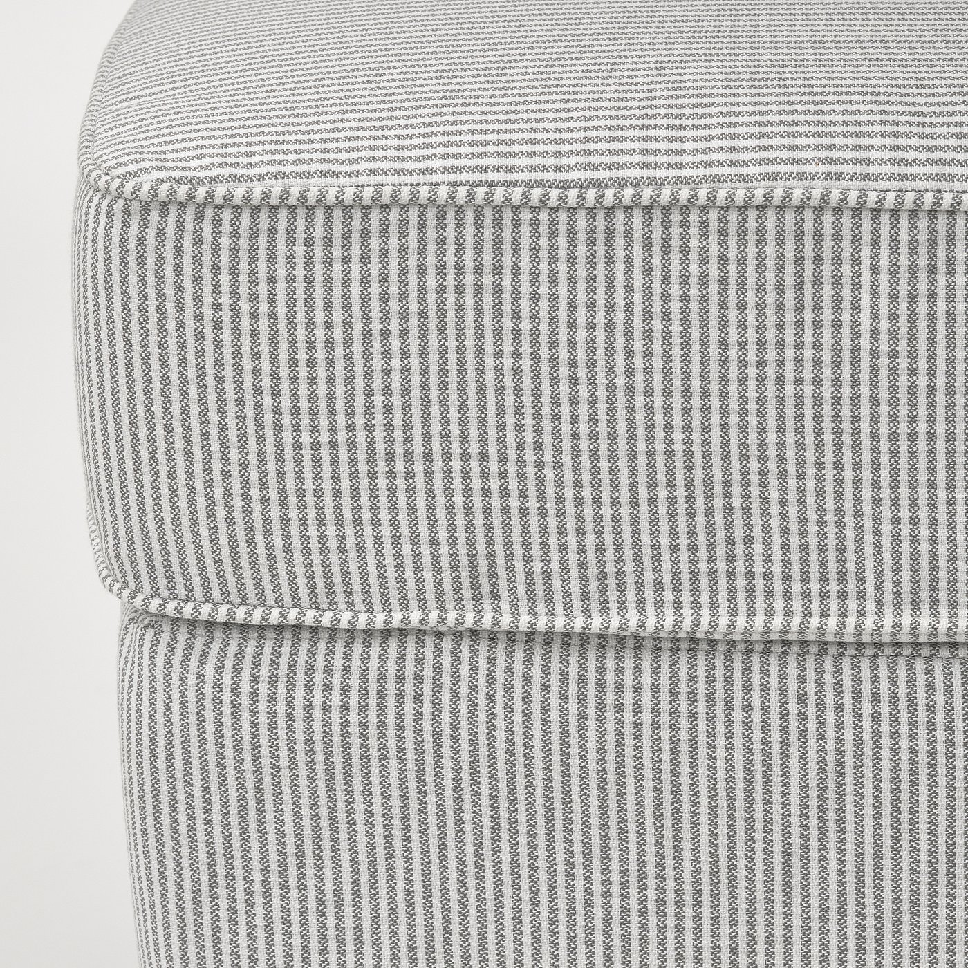 Close-up of striped, textured upholstery on a high-quality, cushioned footstool.