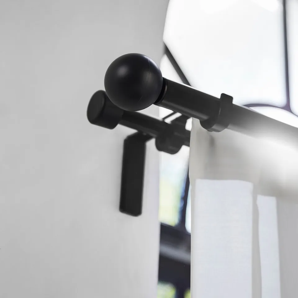 Black VÄSENTLIG finial, round, matte, attached to rod, smaller than curtain.