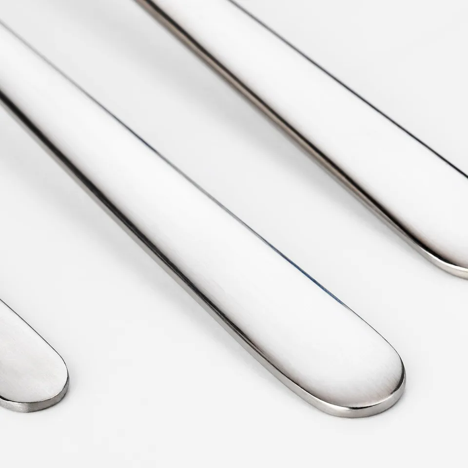 Polished stainless steel cutlery: forks, spoons, neatly arranged. Shiny, modern design.