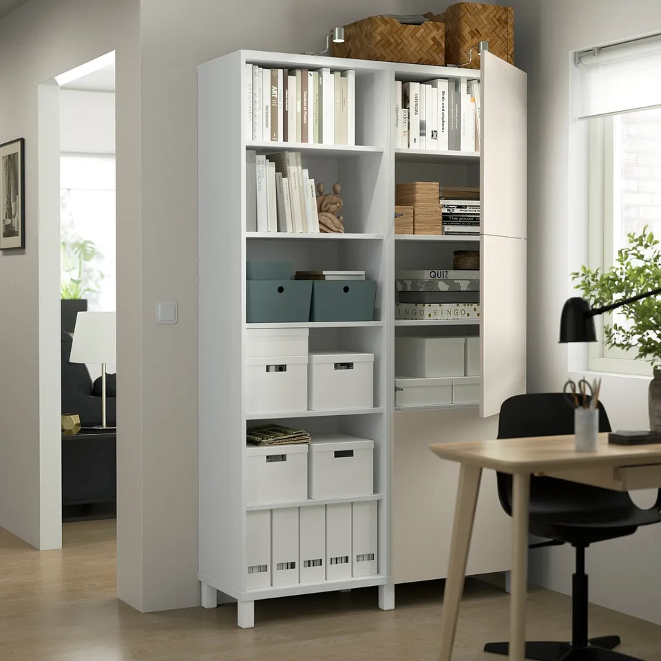 BESTÅ unit with books, decor, and drawers against wall. Nearby desk and chair, doorway.