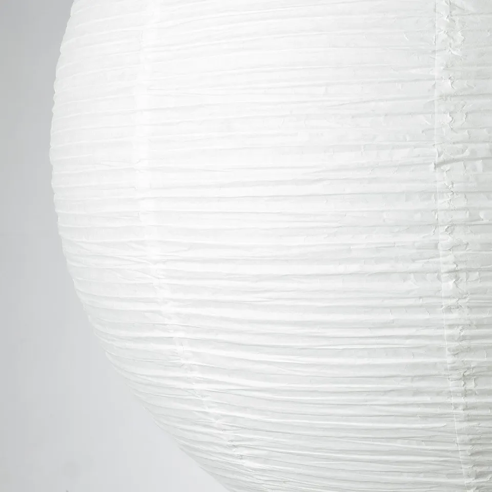 Close-up of a handcrafted white paper lantern, showing its delicate ribbed texture and intricate design details.
