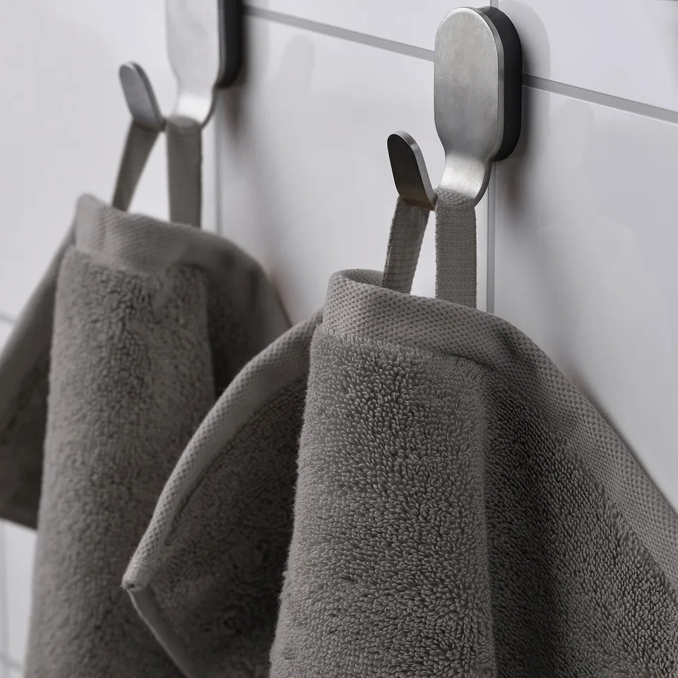 Grey towels hang on metal hooks, showcasing their plush texture and practical storage.