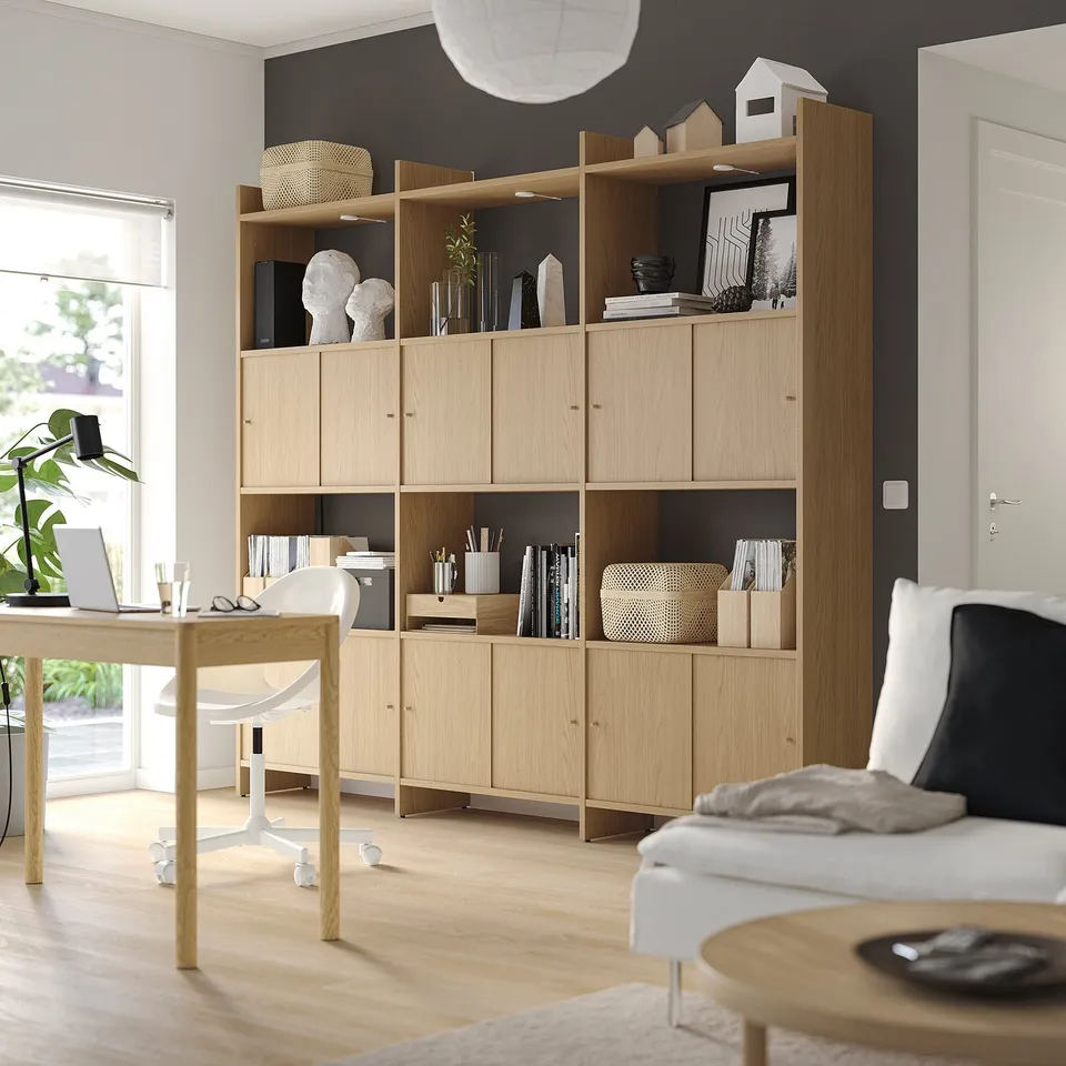 Modern office space with LÅDMAKARE light wood shelves, decor, white couch, desk, and large window.