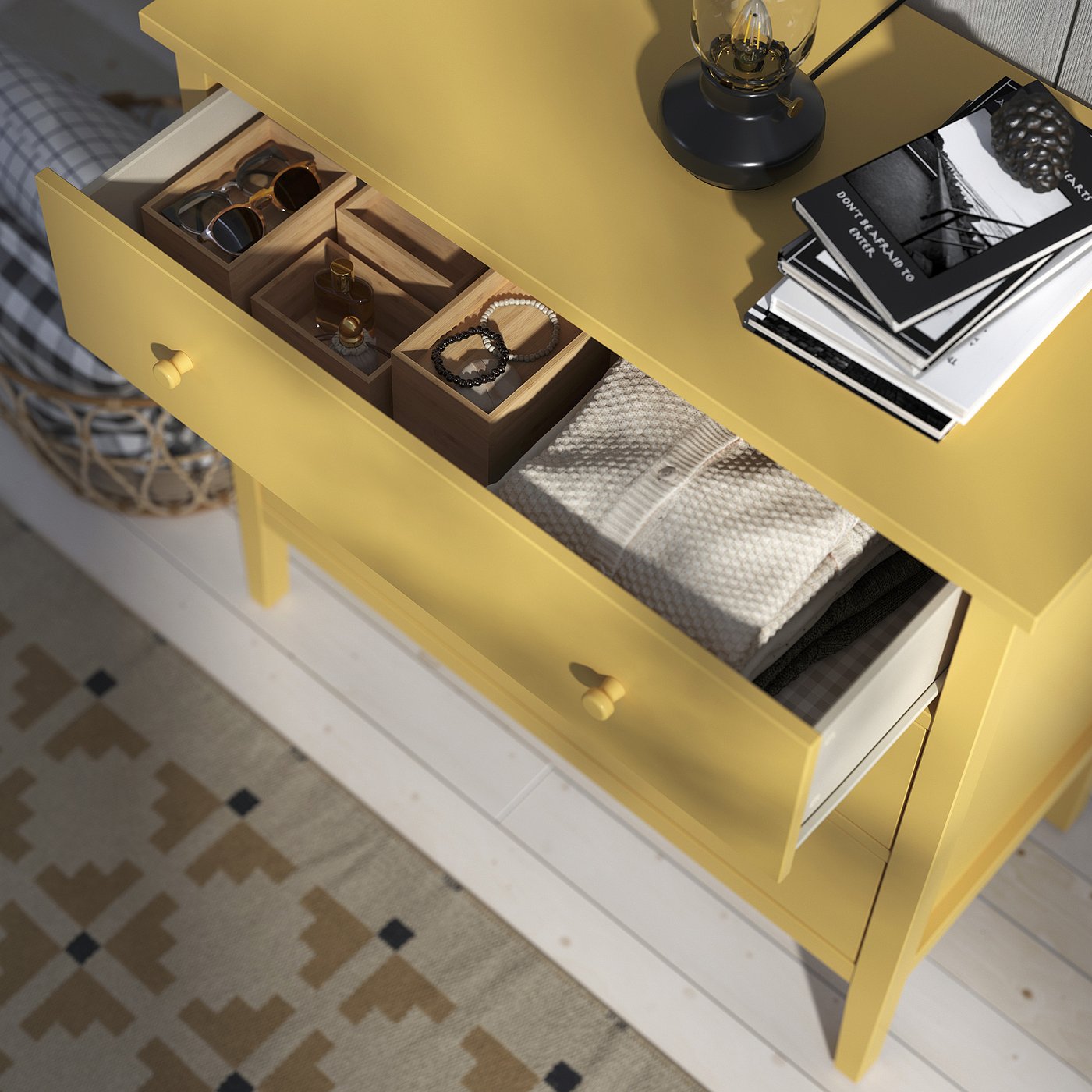 Yellow GULLABERG dresser with open drawers showing jewellery boxes and folded clothes. Top has a lamp and stack of magazines.